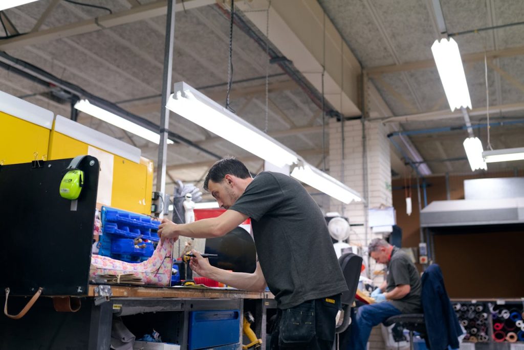 A worker in a factory carefully assembling a product, showcasing precision in injection molding and brush manufacturing processes.